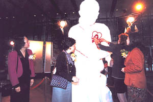 在汇丰银行总行地面广场举行「爱滋病十年回顾图片展览」，由前港督彭定康夫人为石膏像带上红丝带